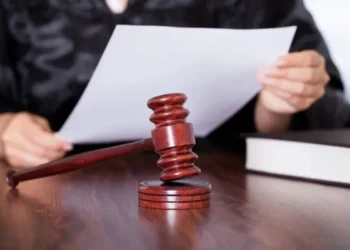 Juiz segurando um documento enquanto bate com o martelo, simbolizando uma decisão judicial.