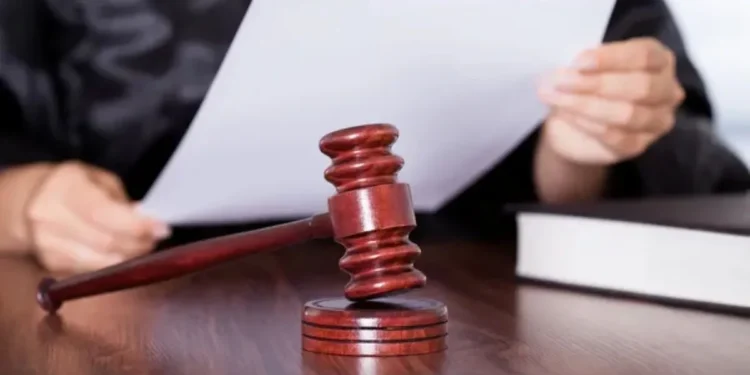 Juiz segurando um documento enquanto bate com o martelo, simbolizando uma decisão judicial.