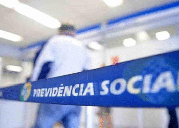Fila de atendimento no INSS, com faixa destacando 'Previdência Social