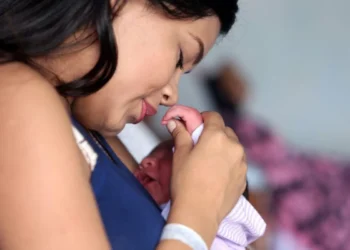 Mãe jovem segurando seu bebê com carinho.