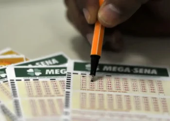 Pessoa marcando números em um bilhete de aposta da Mega-Sena, jogo de loteria popular do Brasil.