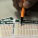 Pessoa marcando números em um bilhete de aposta da Mega-Sena, jogo de loteria popular do Brasil.