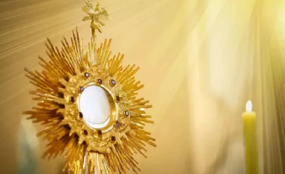 Ostensório dourado com hóstia central iluminada, símbolo do Corpus Christi.