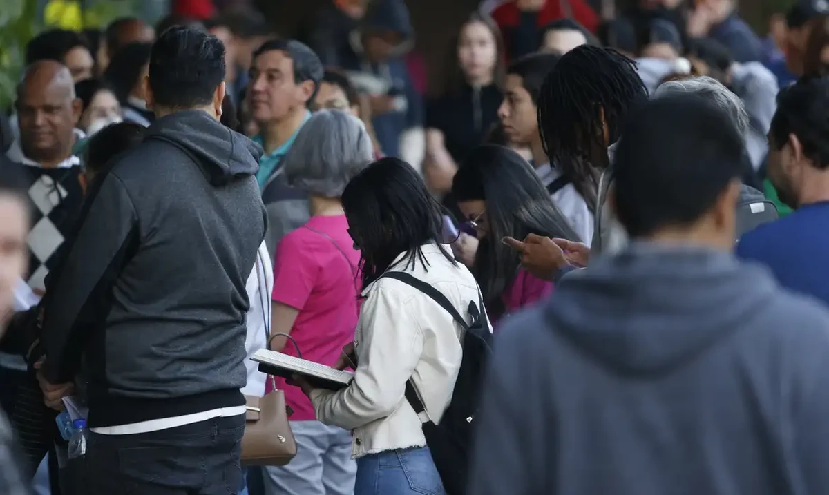 Pessoas em fila aguardando atendimento, ilustrando a organização para o pagamento da primeira parcela do 13º salário antecipado pelo governo estadual.
