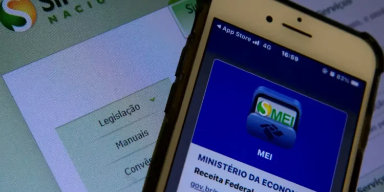 Tela de aplicativo do MEI no celular com site de legislação aberta ao fundo