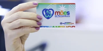 Cartão Mães de Pernambuco com fundo colorido, exibido por uma pessoa com unhas pintadas de rosa.