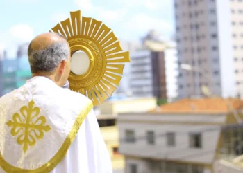 Sacerdote segurando o ostensório durante a celebração de Corpus Christi em ambiente urbano
