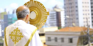 Sacerdote segurando o ostensório durante a celebração de Corpus Christi em ambiente urbano