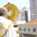 Sacerdote segurando o ostensório durante a celebração de Corpus Christi em ambiente urbano