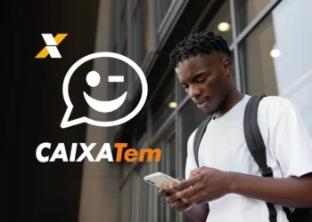 Homem olhando celular com o logo do Caixa Tem em destaque. Imagem relacionada à instabilidade do aplicativo Caixa Tem no pagamento do PIS.