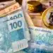 Notas de dinheiro e moedas do real, com destaque para as cédulas de 100 e 50 reais.
