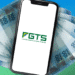 Celular com o aplicativo do FGTS e notas de 100 reais ao fundo.