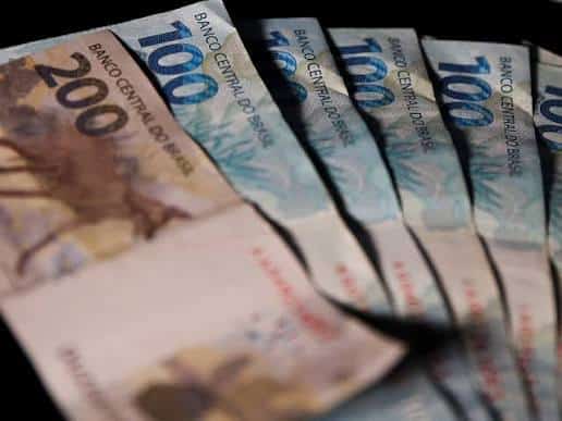Notas de 100 e 200 reais do Banco Central do Brasil enfileiradas lado a lado com foco no valor