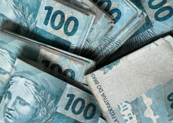 Cédulas de R$ 100 empilhadas representando o valor do Auxílio Emergencial que pode ser recebido do governo.