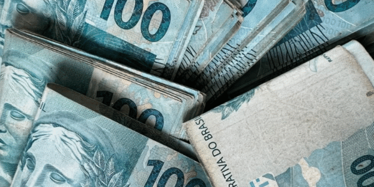 Cédulas de R$ 100 empilhadas representando o valor do Auxílio Emergencial que pode ser recebido do governo.