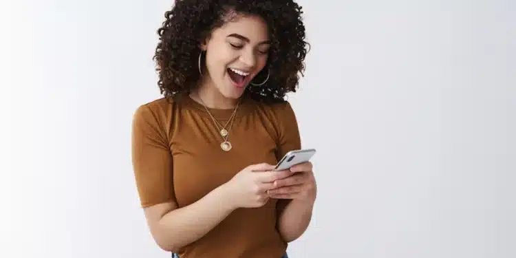 Mulher sorrindo enquanto usa o celular, simbolizando o uso de aplicativos para antecipação de salário.