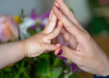 Criança e mãe com as mãos se tocando, simbolizando união e acolhimento