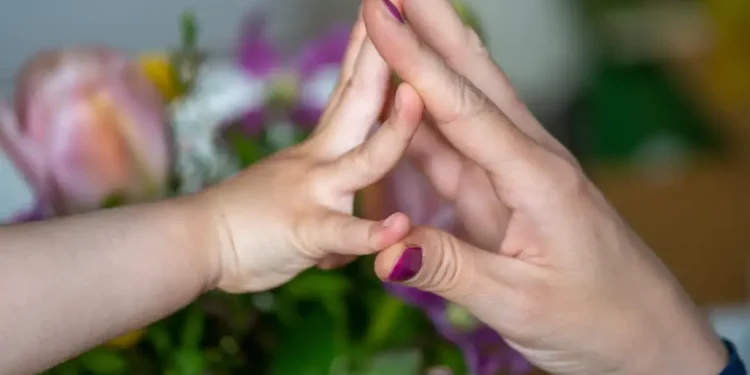 Criança e mãe com as mãos se tocando, simbolizando união e acolhimento