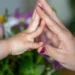Criança e mãe com as mãos se tocando, simbolizando união e acolhimento