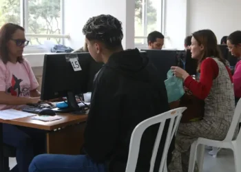 Pessoas sendo atendidas em guichês de assistência social com uso de computador