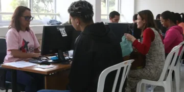 Pessoas sendo atendidas em guichês de assistência social com uso de computador
