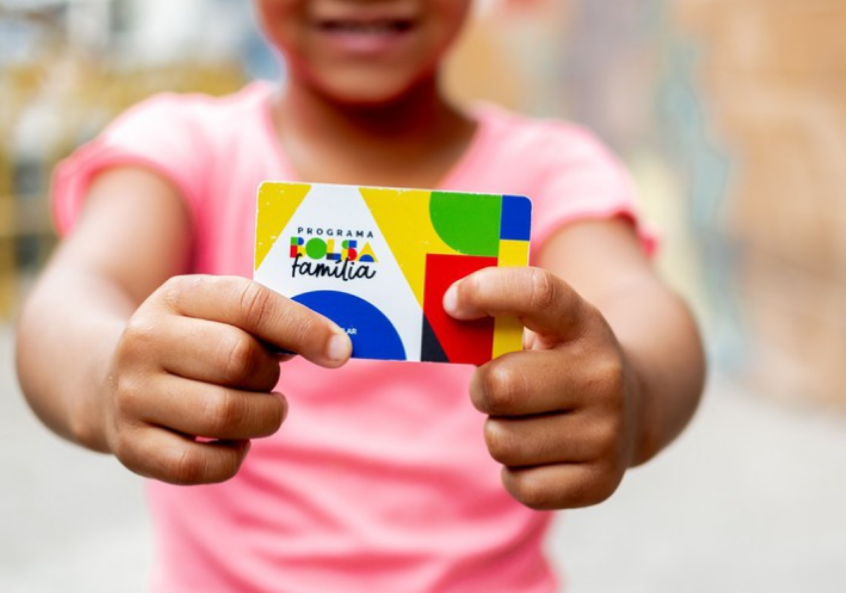 Criança segurando cartão do Programa Bolsa Família.