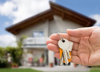 Pessoa segurando um molho de chaves em frente a uma casa