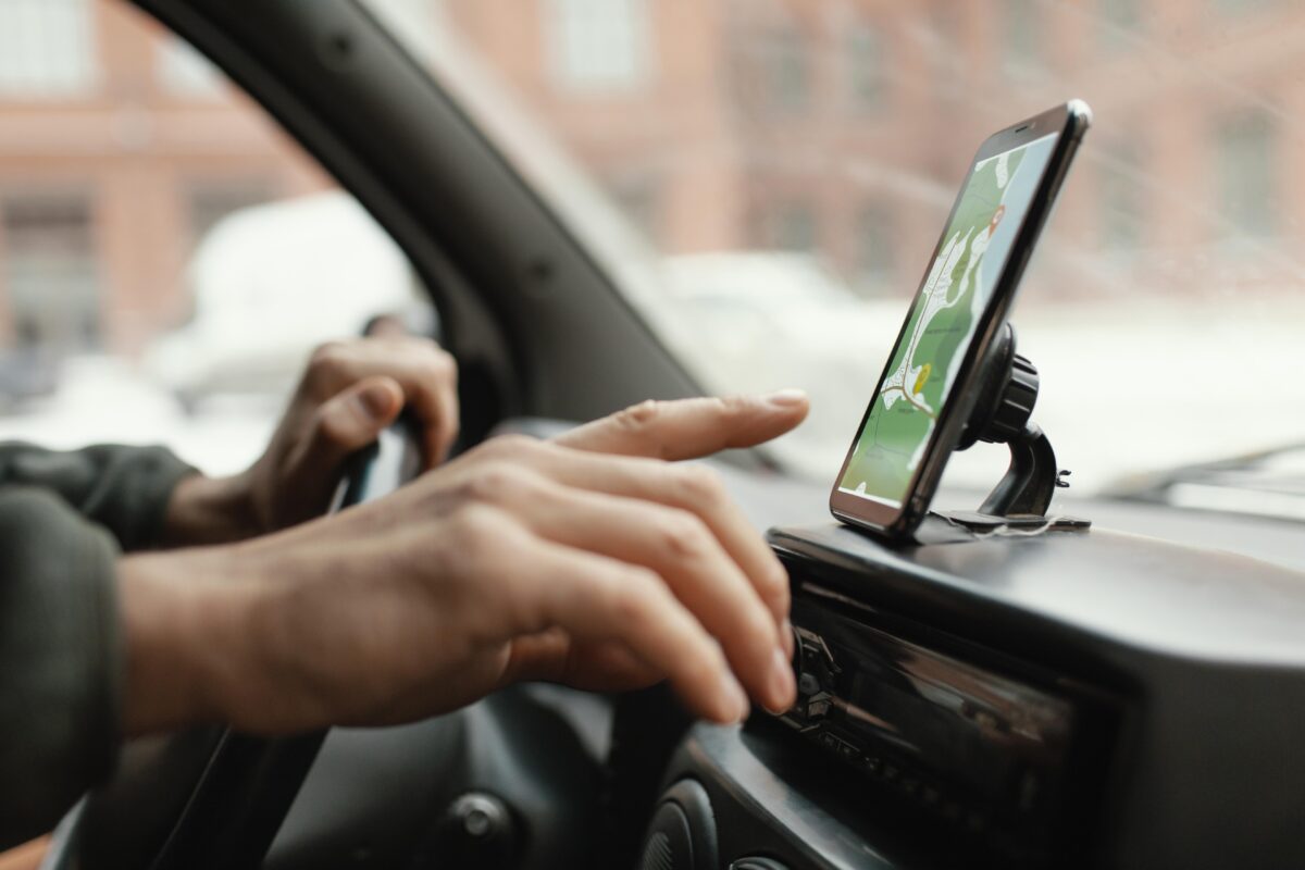Motorista operando GPS no celular dentro do carro.