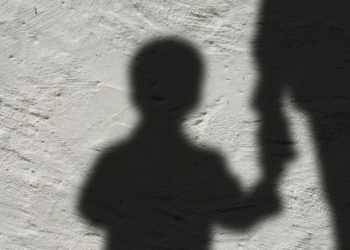Silhueta de uma criança segurando a mão de um adulto, representando o auxílio para órfãos de feminicídio.