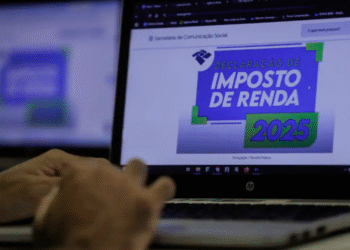 Tela de computador exibindo o site da Receita Federal com a seção de Declaração de Imposto de Renda 2025, enquanto uma mão usa o teclado.