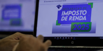 Tela de computador exibindo o site da Receita Federal com a seção de Declaração de Imposto de Renda 2025, enquanto uma mão usa o teclado.