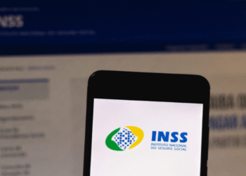 Tela de celular exibindo o logo do INSS com calendário de pagamentos de beneficiários ao fundo.