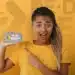 Imagem de uma jovem mulher segurando um celular com o logo e a frase 'Pé de Meia' visíveis na tela.