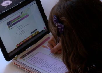 Aluna da rede pública estudando com tablet e material impresso