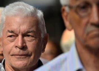 Homem idoso de cabelos brancos participando de evento ao ar livre, com expressão serena