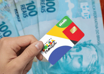 Cartão do programa Bolsa Família com notas de 100 reais ao fundo.Cartão do programa Bolsa Família com notas de 100 reais ao fundo.