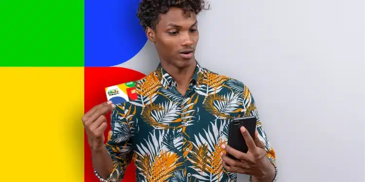Homem segurando um cartão do Bolsa Família e olhando para seu celular, com fundo colorido.