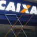 Fachada da agência da Caixa Econômica Federal, destacando o logotipo iluminado em azul e laranja.