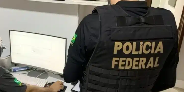 Agentes da Polícia Federal trabalhando no computador durante a campanha nacional de desaparecidos, utilizando tecnologia para localizar e identificar pessoas desaparecidas.