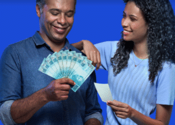 Casal sorridente segurando cédulas de R$ 100 e cupom fiscal