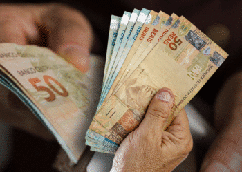 Notas de 50 reais sendo contadas por mãos humanas