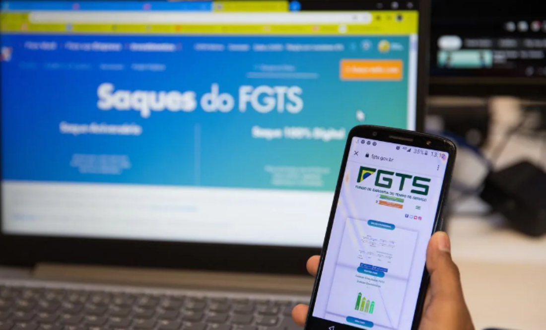 Pessoa acessando o site do FGTS pelo celular e computador.