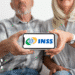 Casal de aposentados segura celular com logo do INSS, representando nova fase do reembolso