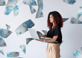 Imagem de uma mulher sorrindo enquanto trabalha no laptop, com dinheiro voando ao seu redor, simbolizando oportunidades financeiras.