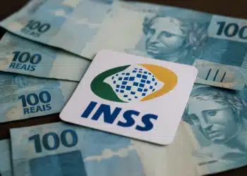 Dinheiro e o logo do INSS, simbolizando o pagamento de benefícios e a liberação de valores.