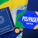 Cartão PIS/PASEP Caixa ao lado da carteira de trabalho e dinheiro sobre bandeira do Brasil.