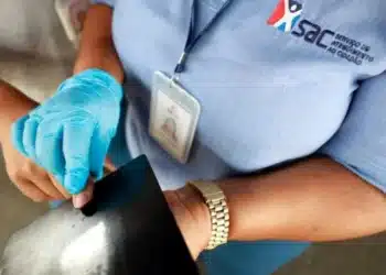 Funcionário do SAC usando luvas enquanto emite a carteira de identidade.