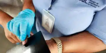 Funcionário do SAC usando luvas enquanto emite a carteira de identidade.