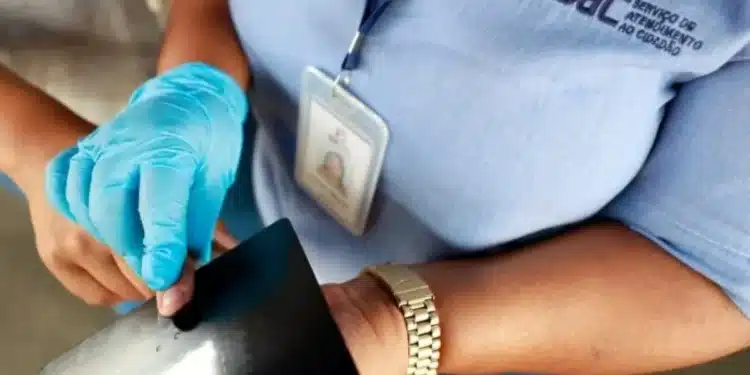 Funcionário do SAC usando luvas enquanto emite a carteira de identidade.