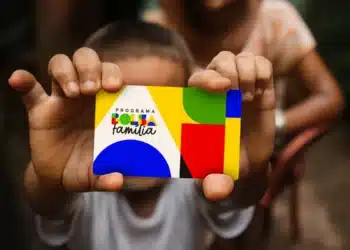 Criança segurando cartão do Programa Bolsa Família com design colorido em amarelo, verde, azul e vermelho